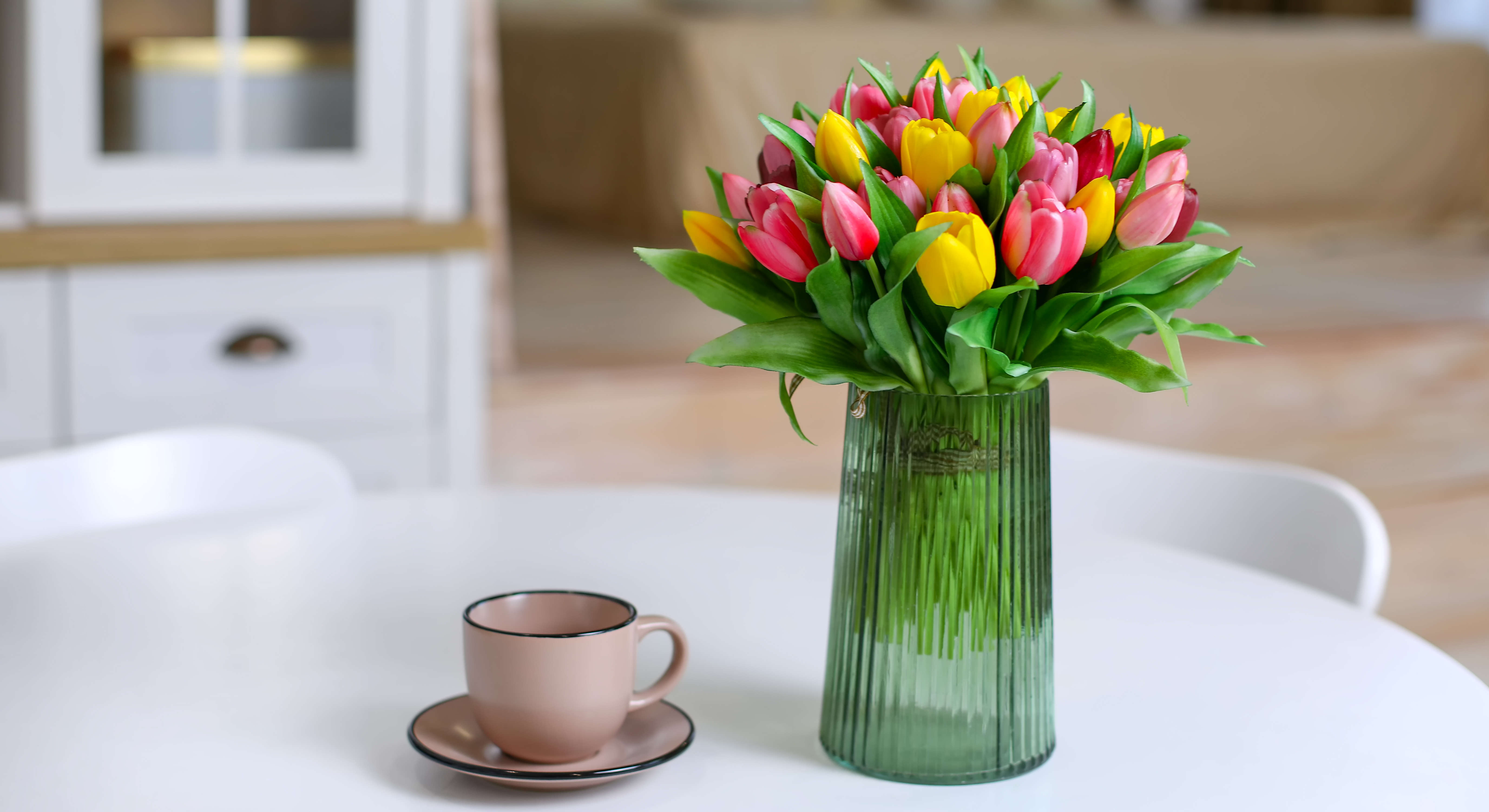 Mixed tulips in a tall glass vase on a coffee table