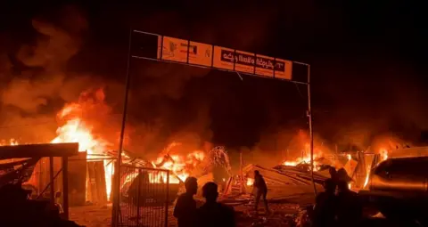 Reuters Fire rages at an area designated for displaced Palestinians in Gaza, 26 May 