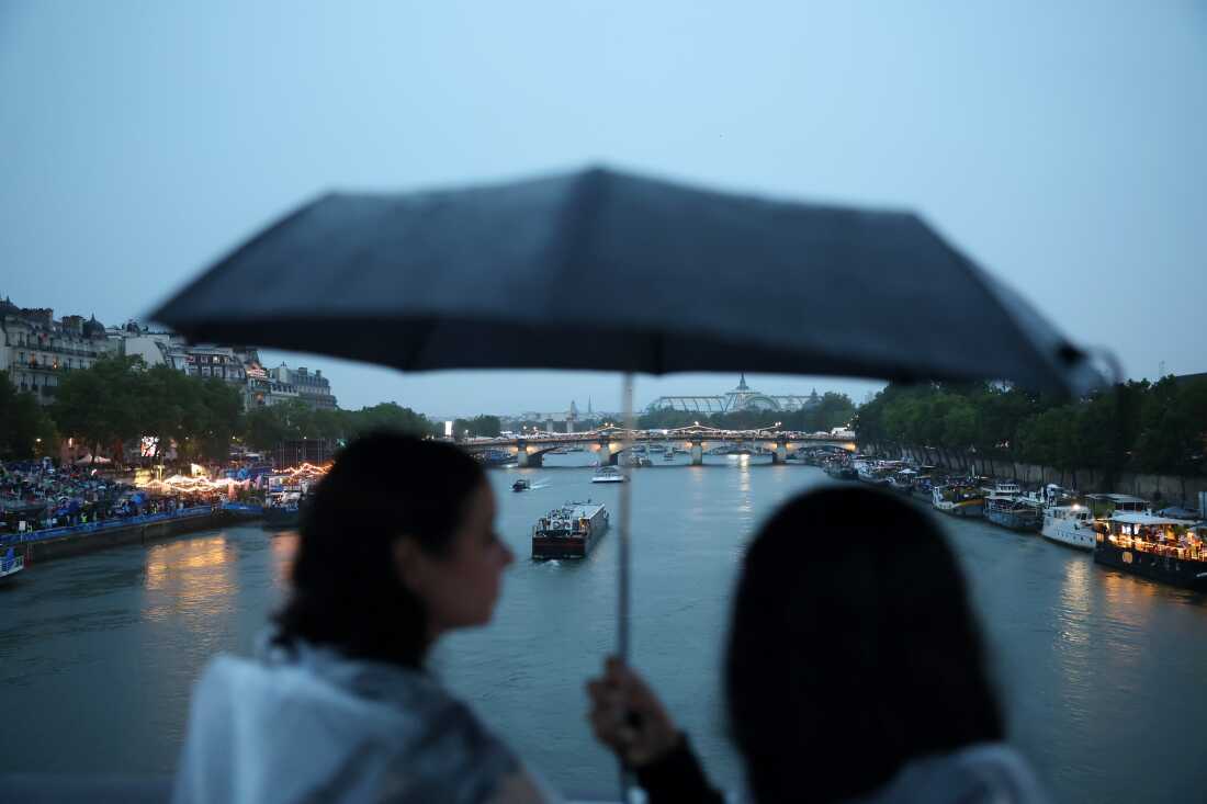 Athlete boats travel along the River Seine as spectators shelter from the rain during the opening ceremony of the Olympic Games Paris 2024 on Friday.