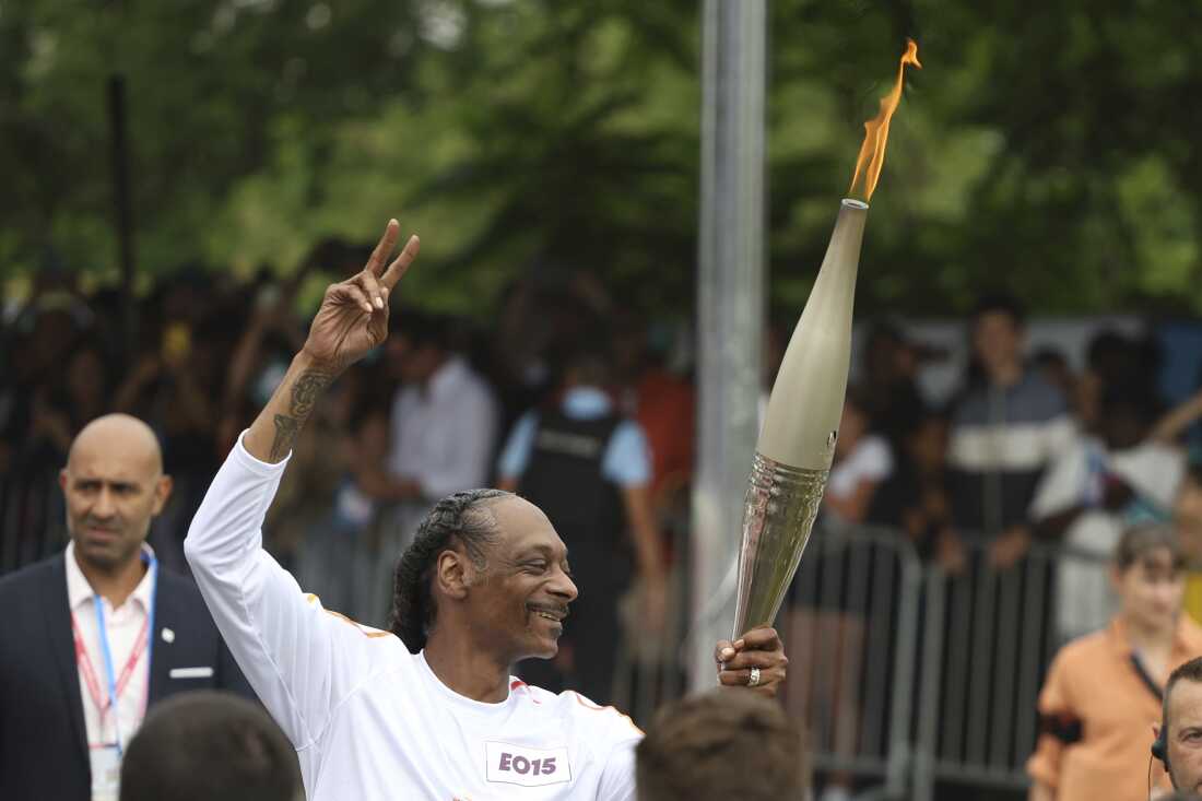 Snoop Dogg carries the Olympic torch at the 2024 Summer Olympics, Friday, July 26, in Saint-Denis, outside Paris, France.