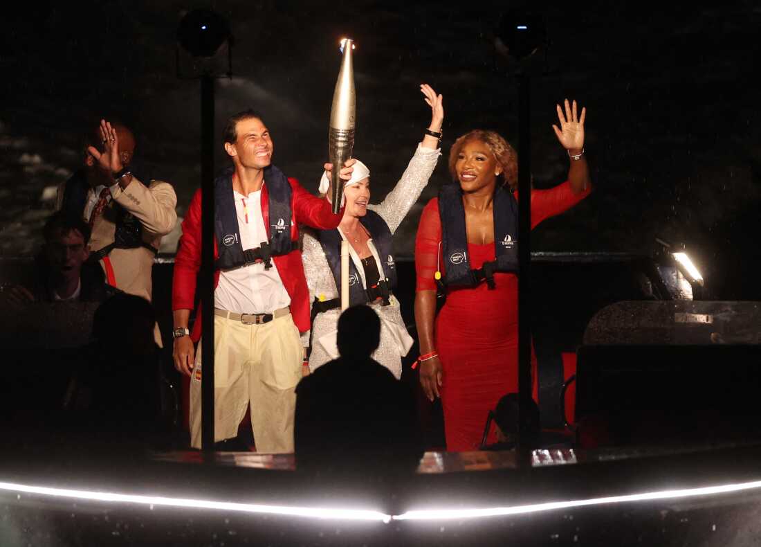 Rafael Nadal holds the Olympic torch alongside Serena Williams on a boat on the river Seine ahead of lighting the Olympic cauldron during the opening ceremony.