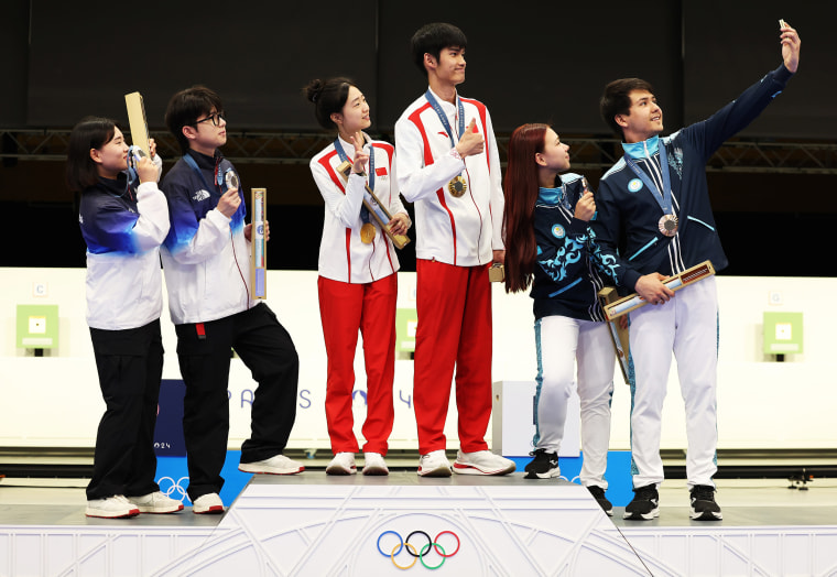 CHATEAUROUX, FRANCE - JULY 27: Gold medalists Yuting Huang and Lihao Sheng of Team Peopleâ€™s Republic of China (L), Silver medalists Hajun Park and Jihyeon Keum of Team Republic of Korea (L) and Bronze medalists Alexandra Le and Islam Satpayev of Team Kazakhstan (R) take a selfie on the podium during the Shooting medal ceremony after the 10m Air Rifle Mixed Team on day one of the Olympic Games Paris 2024 at Chateauroux Shooting Centre on July 27, 2024 in Chateauroux, France.